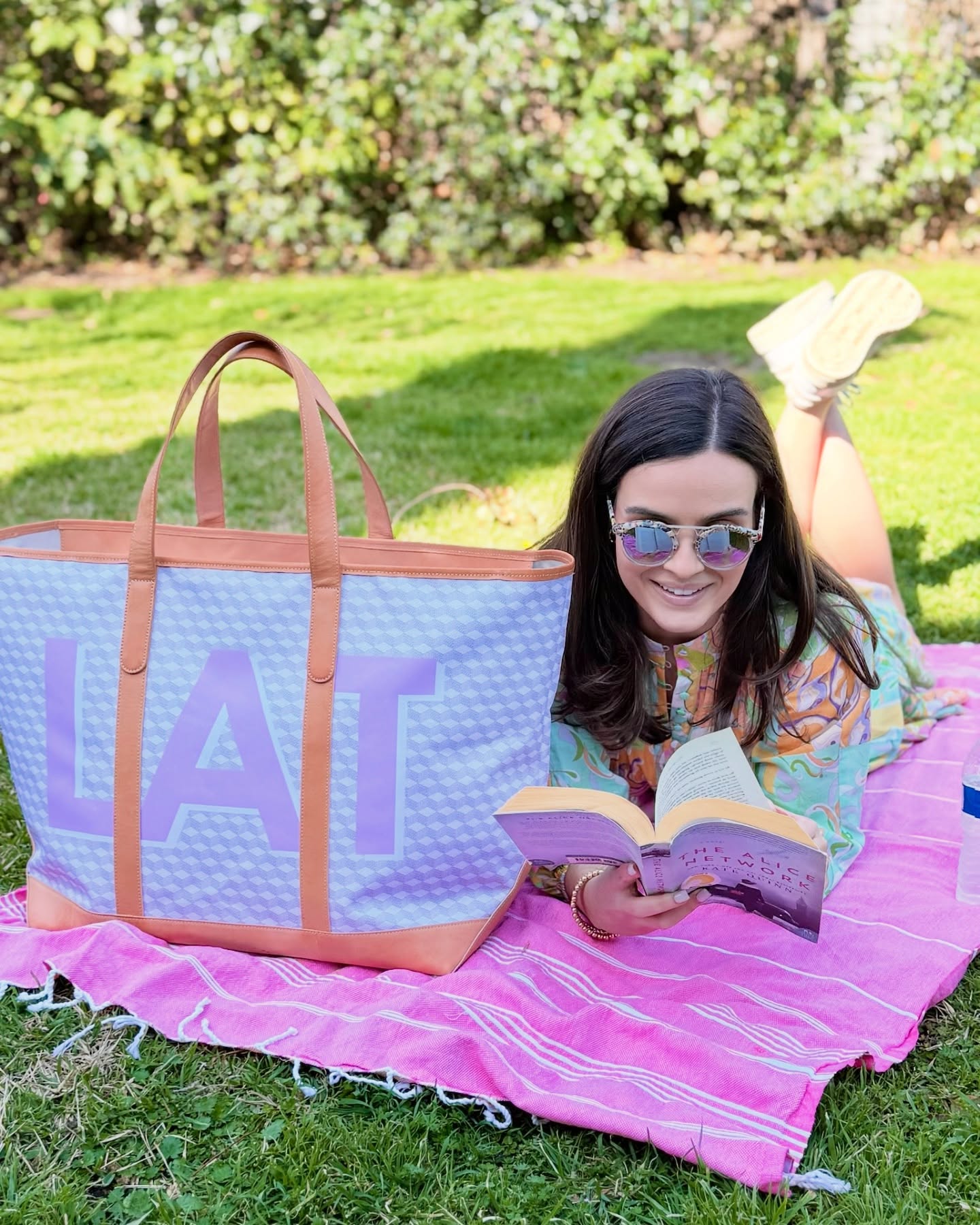 Woman enjoying a read outdoors with a personalized large monogrammed yacht tote bag, a type of monogrammed tote bag.